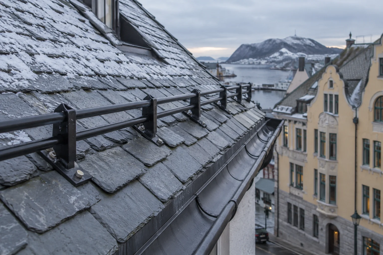 Snøfanger med rør og konsoller over takfoten på et skifertak.